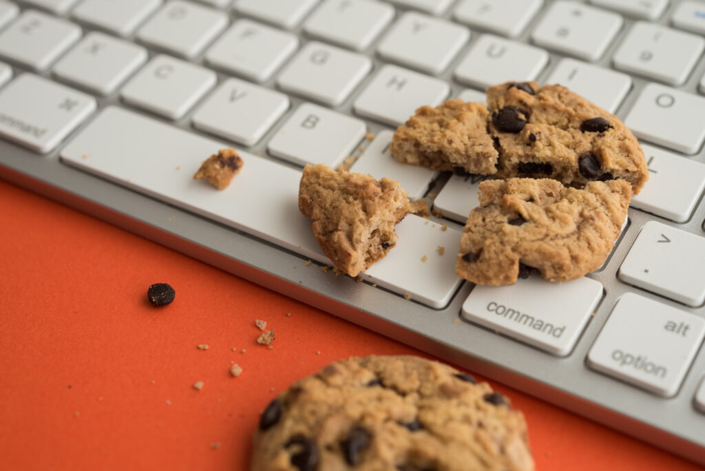 Broken chocolate chip cookies on keyboard computer background.